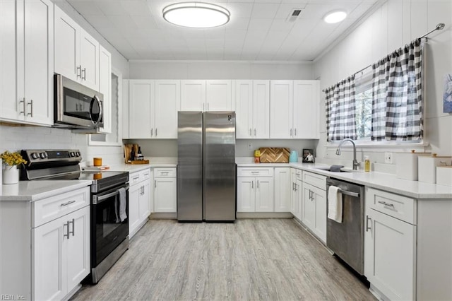 kitchen featuring stainless steel appliances, light wood-style floors, a sink, and white cabinets