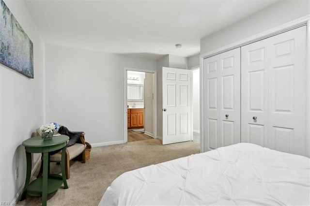 carpeted bedroom with a sink, a closet, connected bathroom, and baseboards