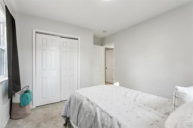 bedroom featuring light carpet, baseboards, and a closet