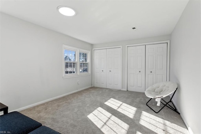 unfurnished bedroom featuring multiple closets, carpet flooring, and baseboards