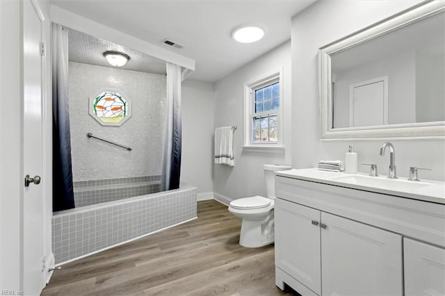 full bath with toilet, a shower with shower curtain, wood finished floors, vanity, and visible vents