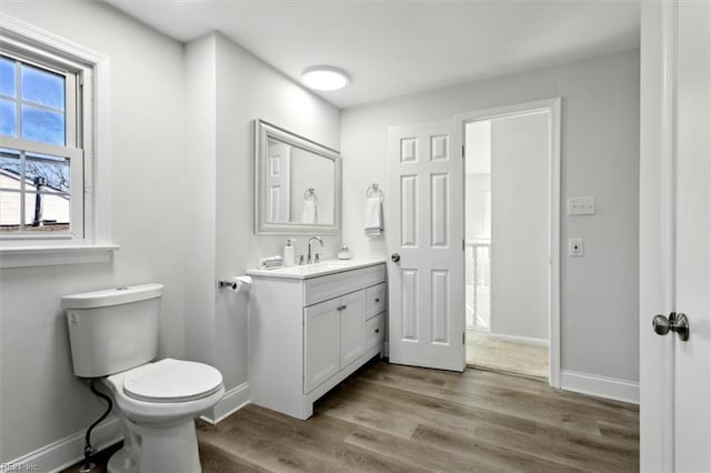 bathroom featuring baseboards, vanity, toilet, and wood finished floors