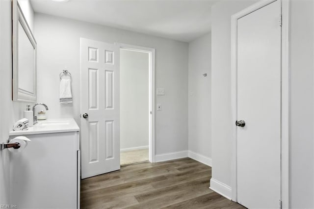 bathroom with wood finished floors, vanity, and baseboards