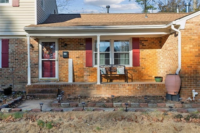 entrance to property featuring brick siding and roof with shingles