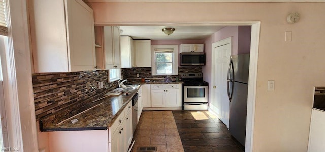 kitchen with sink, dark stone counters, decorative backsplash, white cabinets, and appliances with stainless steel finishes