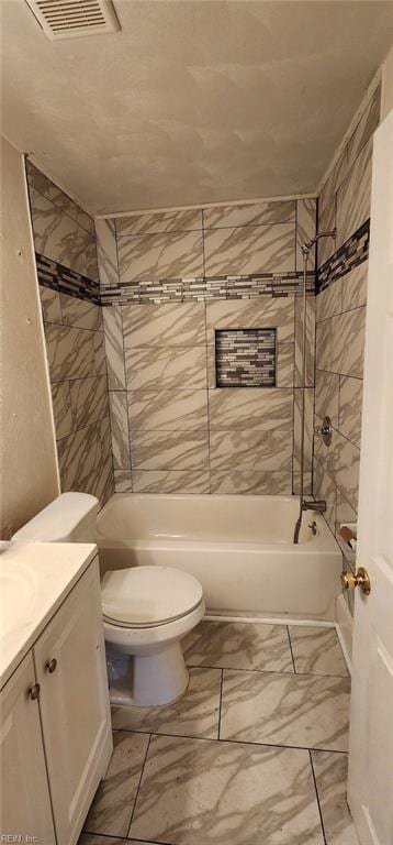 full bathroom featuring tiled shower / bath, vanity, and toilet