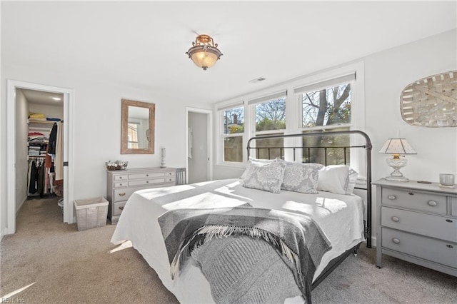 bedroom with light colored carpet, a spacious closet, and a closet