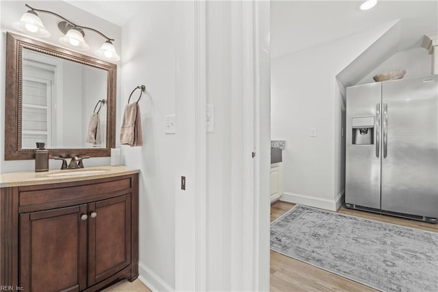 bathroom with vanity, hardwood / wood-style floors, and vaulted ceiling