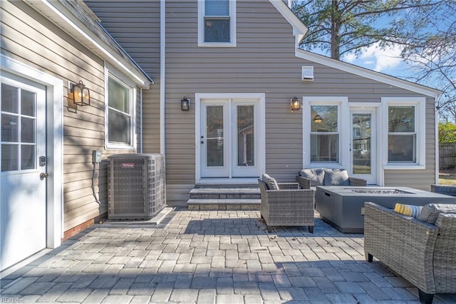 view of patio with an outdoor living space with a fire pit and central air condition unit