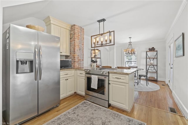 kitchen with appliances with stainless steel finishes, light wood-type flooring, light stone counters, cream cabinets, and decorative light fixtures