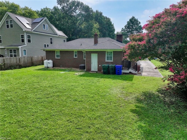 back of property with solar panels and a lawn