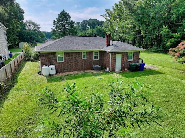 rear view of property with a lawn and cooling unit