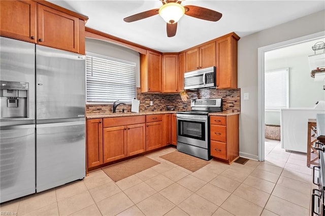 kitchen featuring ceiling fan, sink, stainless steel appliances, decorative backsplash, and light tile patterned floors