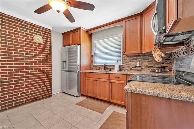 kitchen featuring sink, light stone countertops, tasteful backsplash, stainless steel appliances, and brick wall