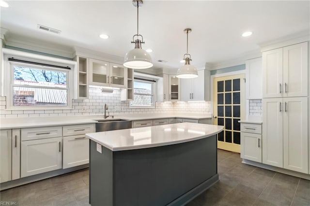 kitchen featuring a center island, sink, hanging light fixtures, a healthy amount of sunlight, and white cabinetry