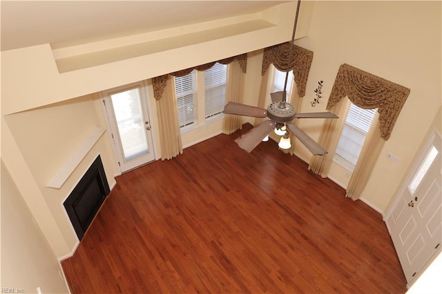 unfurnished living room featuring dark wood-type flooring and ceiling fan