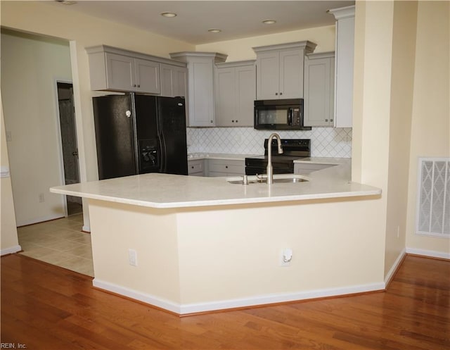 kitchen featuring sink, decorative backsplash, black appliances, and kitchen peninsula