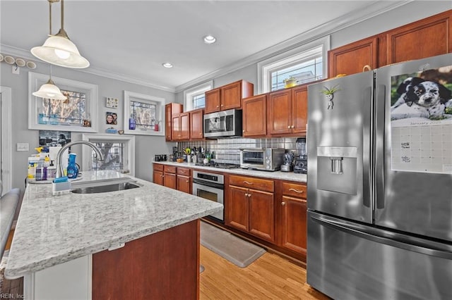 kitchen with appliances with stainless steel finishes, tasteful backsplash, a kitchen island with sink, sink, and pendant lighting