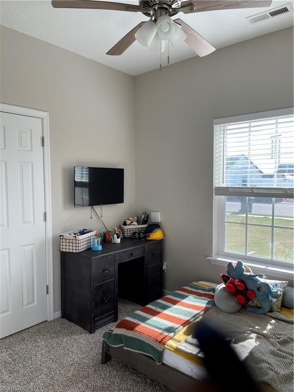 carpeted bedroom with visible vents and a ceiling fan