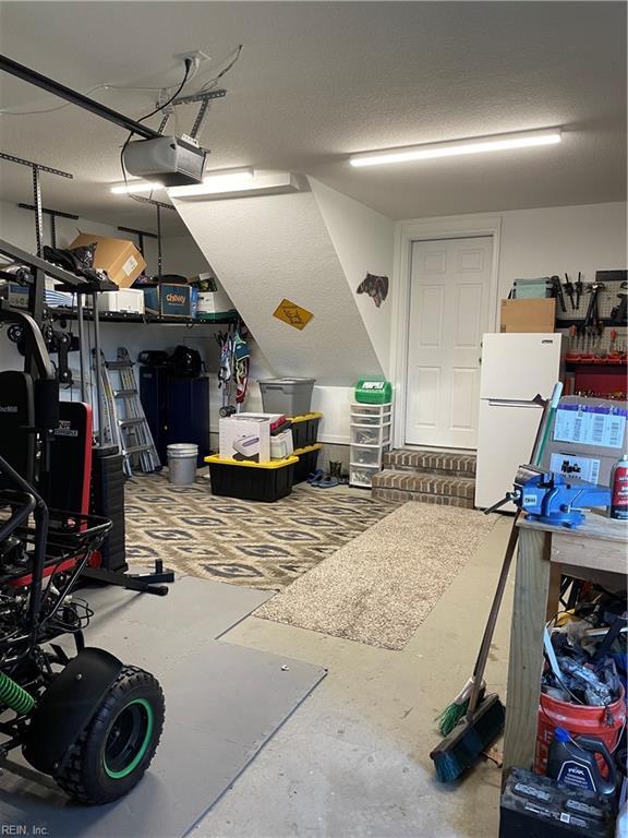 garage with a garage door opener and freestanding refrigerator