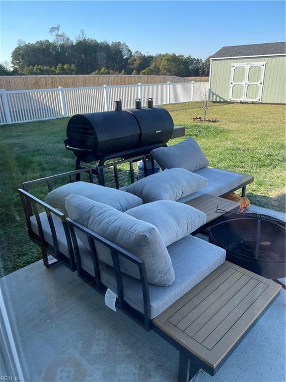 view of patio / terrace with a storage shed, an outdoor fire pit, an outbuilding, and fence