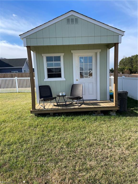 back of house with a deck, an outdoor structure, a lawn, and fence