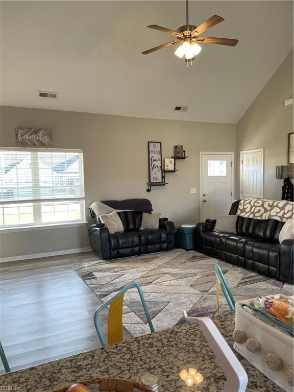 living room with ceiling fan, plenty of natural light, hardwood / wood-style floors, and high vaulted ceiling