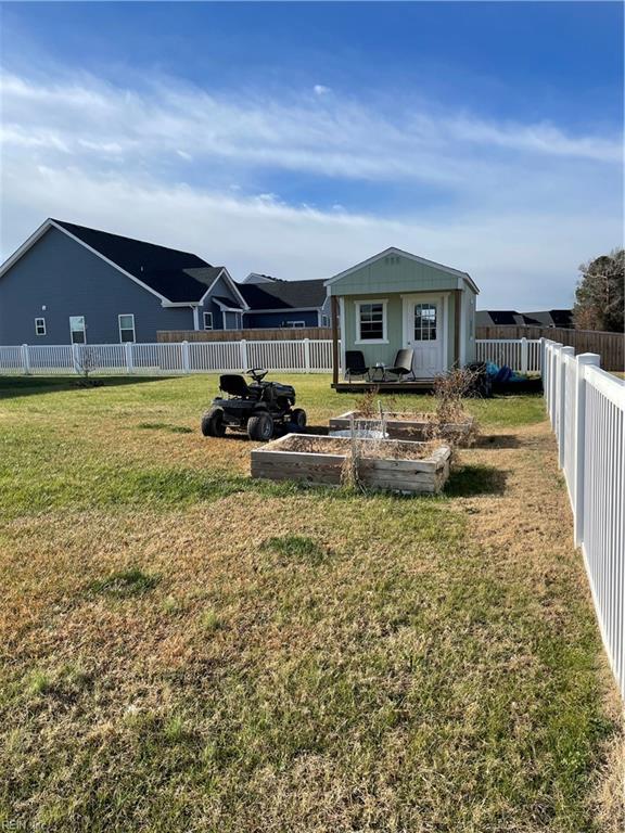 view of yard with a garden, a fenced backyard, and an outbuilding