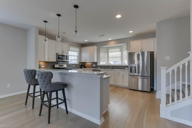 kitchen featuring stainless steel appliances, pendant lighting, white cabinets, and sink