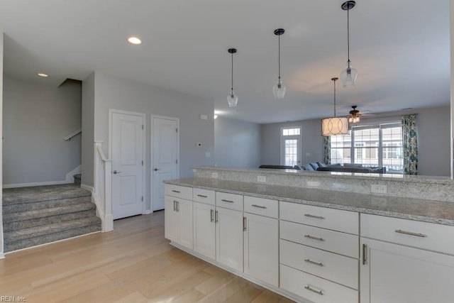 kitchen featuring light hardwood / wood-style floors, ceiling fan, decorative light fixtures, light stone countertops, and white cabinets