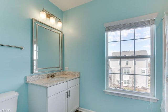 bathroom with toilet, vanity, and a wealth of natural light