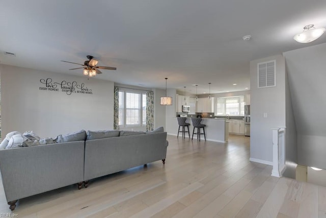 living room featuring ceiling fan, light wood-type flooring, and sink