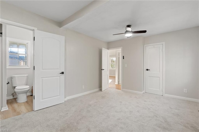 unfurnished bedroom with light carpet, ensuite bath, and ceiling fan