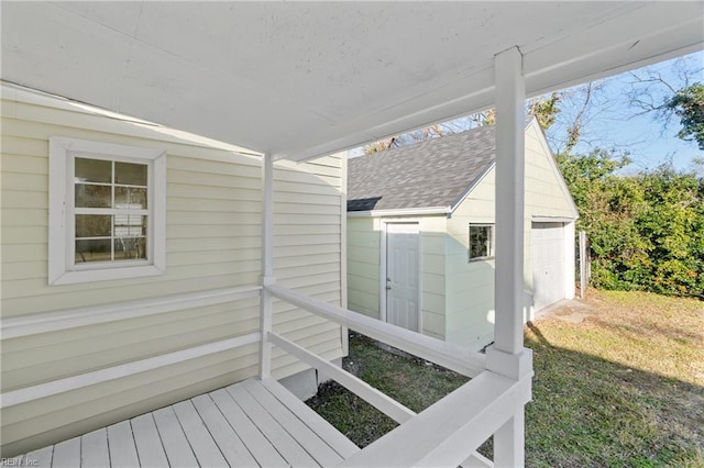 deck featuring a lawn, an outbuilding, and a garage