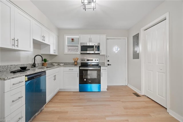 kitchen with white cabinets, sink, light wood-type flooring, light stone counters, and stainless steel appliances