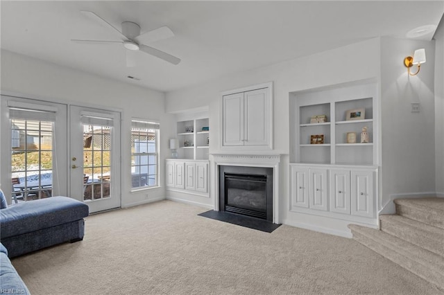 living room with french doors, light colored carpet, ceiling fan, and built in shelves