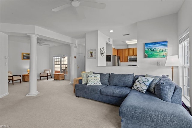 living room with decorative columns, ceiling fan, and plenty of natural light