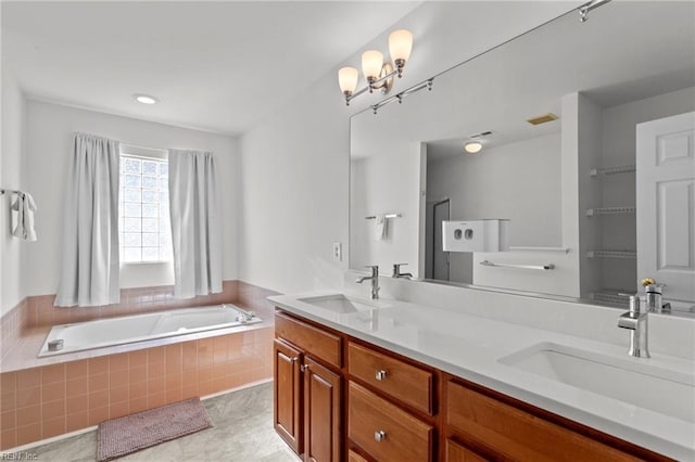 bathroom with tiled bath, tile patterned flooring, and vanity