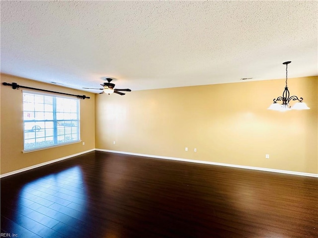 spare room with a textured ceiling, ceiling fan with notable chandelier, and dark wood-type flooring