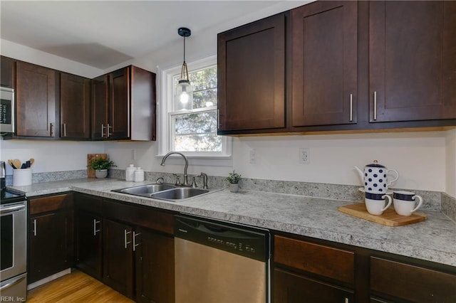 kitchen with appliances with stainless steel finishes, light wood-type flooring, dark brown cabinetry, sink, and hanging light fixtures