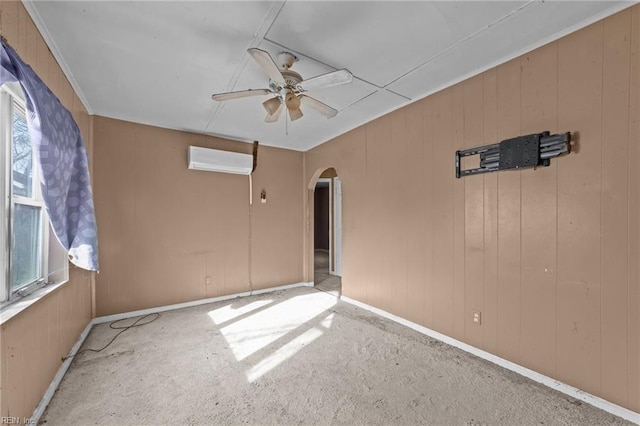 carpeted empty room featuring ceiling fan, wooden walls, and a wall mounted air conditioner