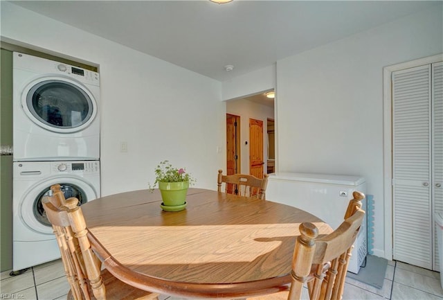 tiled dining room featuring stacked washing maching and dryer