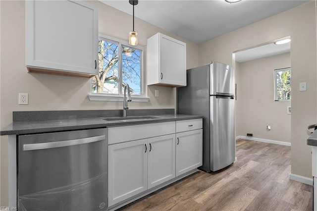 kitchen featuring sink, stainless steel appliances, decorative light fixtures, white cabinets, and hardwood / wood-style flooring