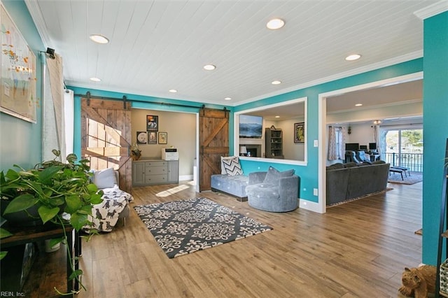 living room featuring hardwood / wood-style floors, a barn door, wooden ceiling, and crown molding