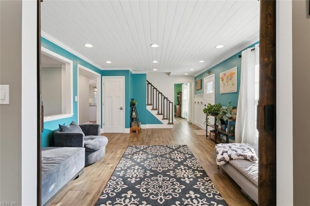 living room featuring ornamental molding, light hardwood / wood-style flooring, and wooden ceiling