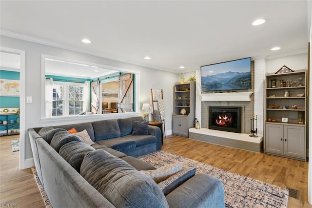 living room with crown molding, light hardwood / wood-style flooring, and a brick fireplace