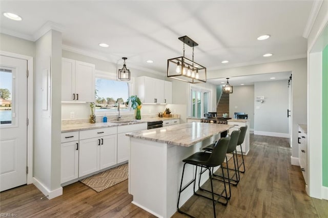 kitchen with white cabinets, dark hardwood / wood-style floors, a kitchen island, and light stone countertops