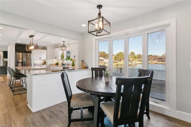 dining room with a chandelier, light wood-type flooring, and a water view