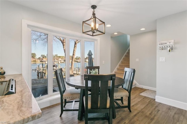 dining room with a notable chandelier, a water view, and wood-type flooring