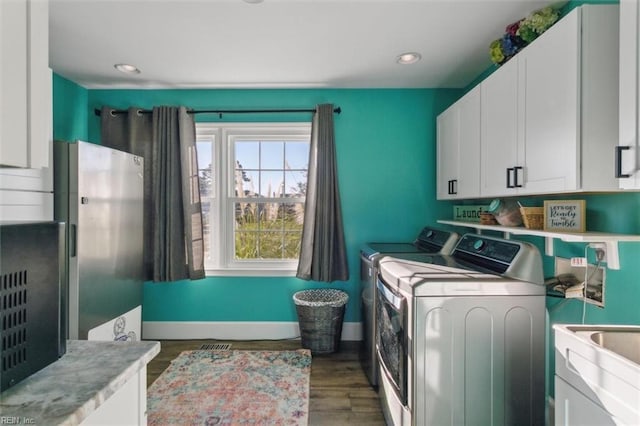 clothes washing area featuring sink, washer and dryer, cabinets, and dark wood-type flooring